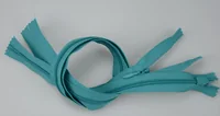 Teal nylon coil zippers coiled together on a plain white background