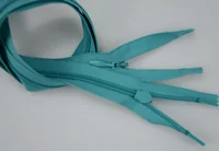 Coiled teal nylon zippers with plastic sliders on a light gray surface