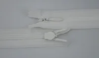 Two white nylon coil zippers with metal and plastic sliders on a plain light background