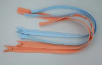 Two closed-end zippers, one light blue and one orange, arranged in loops on a plain white surface