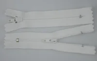 Two white zippers with sliders laid flat on a plain light background