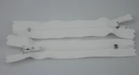 Two white zippers with metal sliders laid flat on a plain gray background
