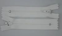 Two white zippers with metal sliders lying parallel on a plain light gray background