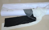 Rolls of white and dark fabric or nonwoven material partially unrolled on a tiled floor