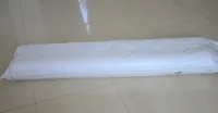 Long object wrapped in white plastic lying on a beige tiled floor