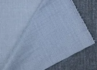Close-up of light blue ribbed knit fabric swatch layered over a dark grey textured fabric background
