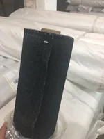 Roll of black woven fabric held in front of stacked wrapped rolls in a warehouse