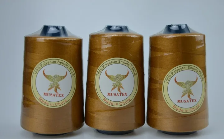 Three golden MUSATEX 100% polyester sewing thread cones with branded phoenix labels on a plain background