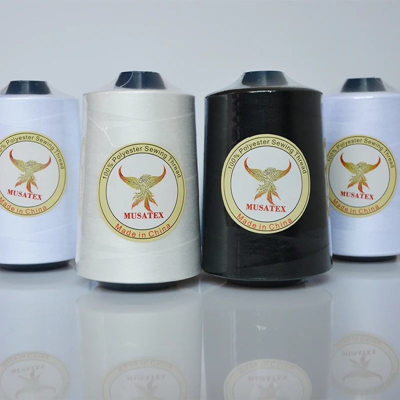 White and black polyester sewing thread cones with MUSATEX phoenix labels on a white reflective surface