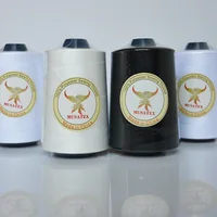 White and black polyester sewing thread cones with MUSATEX phoenix labels on a white reflective surface