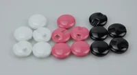 White, pink, and black round plastic cord locks arranged in rows on a plain gray background