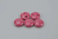 Five glossy pink round plastic buttons, two showing slot holes, arranged on a plain gray background
