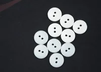 Ten white two-hole round buttons scattered on a dark fabric background