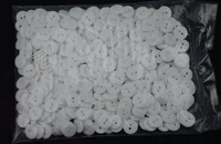 Clear plastic bag filled with white two-hole buttons on a dark background