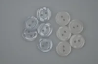 Two groups of two-hole buttons, translucent white on the left and opaque white on the right, on a plain light background.