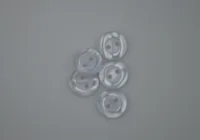 Five translucent white two-hole buttons on a plain gray background