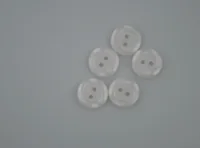 Five white two-hole buttons arranged on a plain light gray background