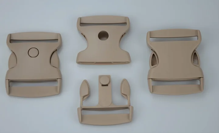 Four tan plastic side-release buckle components arranged on a plain light background.
