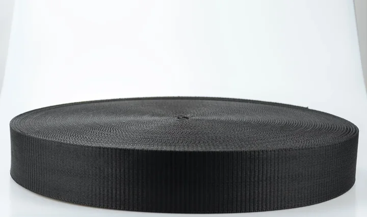 Large roll of black woven webbing strap on a clean white background