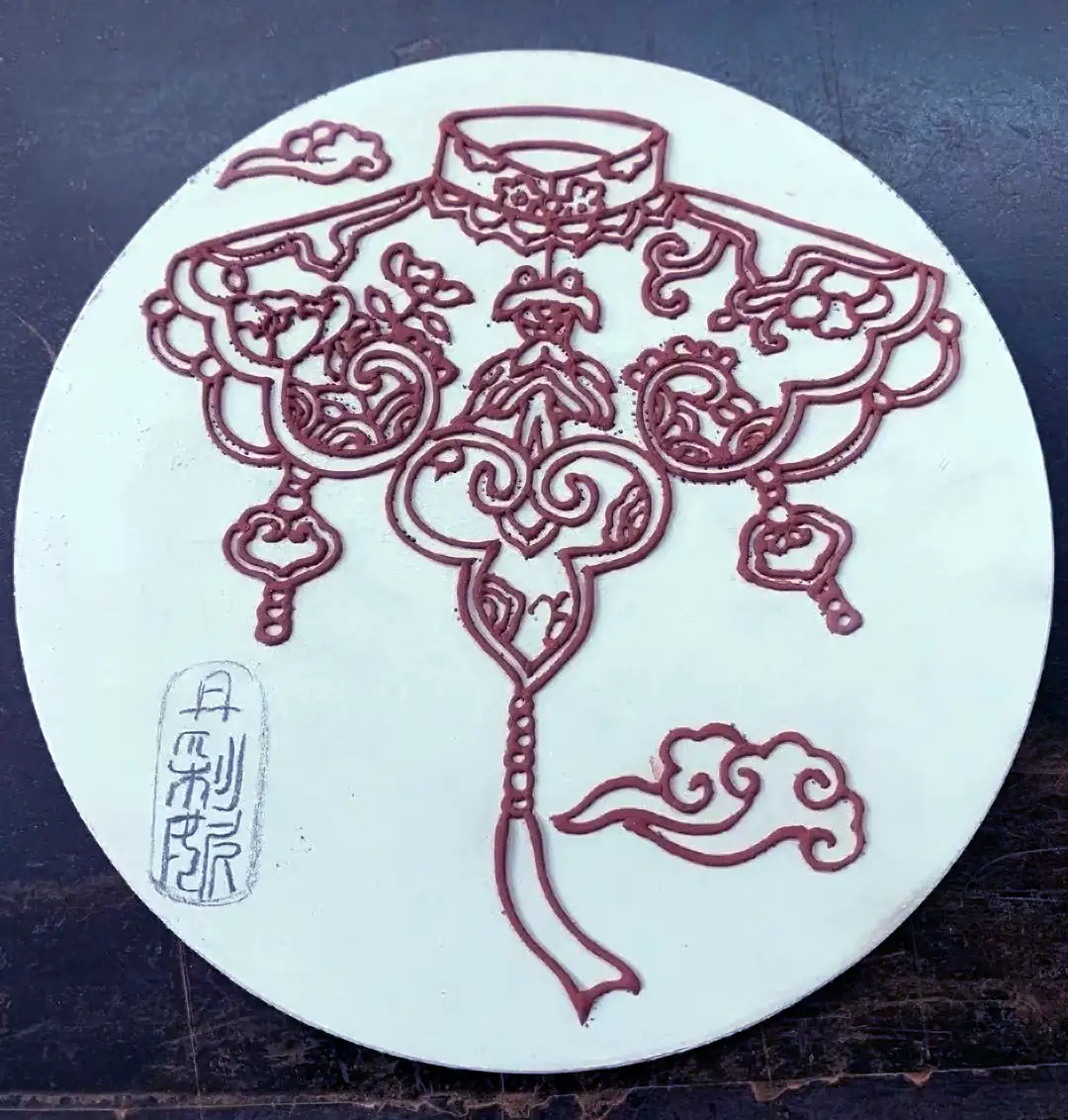 Raised clay outlines applied by hand onto a round porcelain tile blank