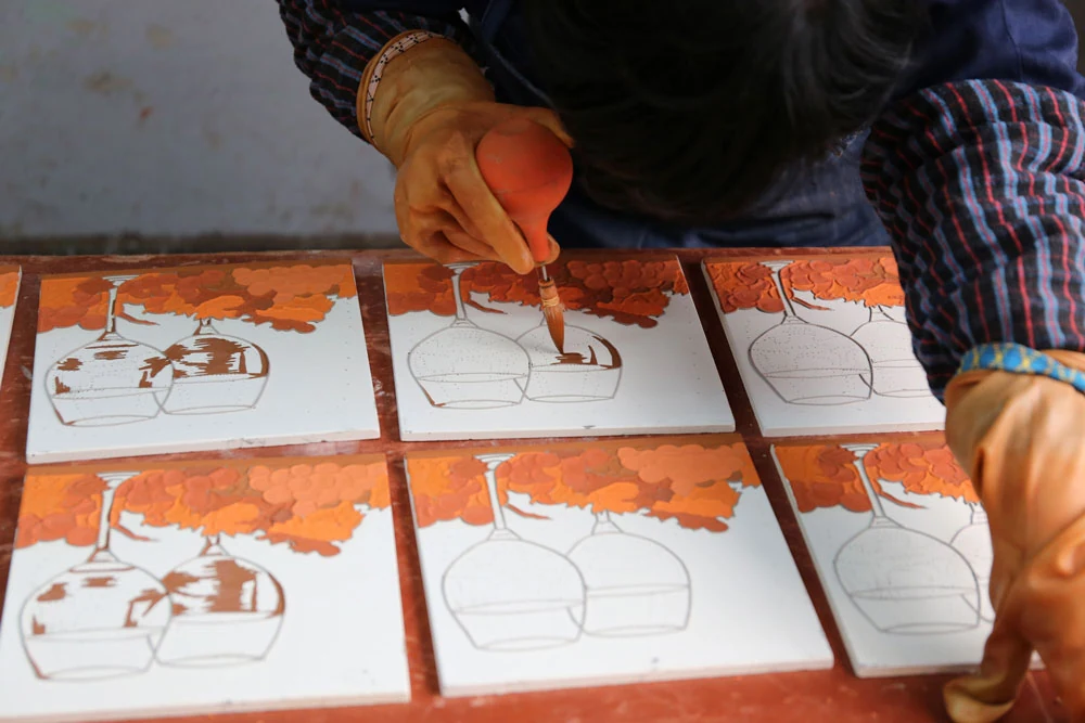 Coloured glaze being applied inside outlined flower panels