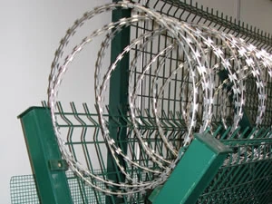 Razor wire coil fixed to a green welded mesh fence panel