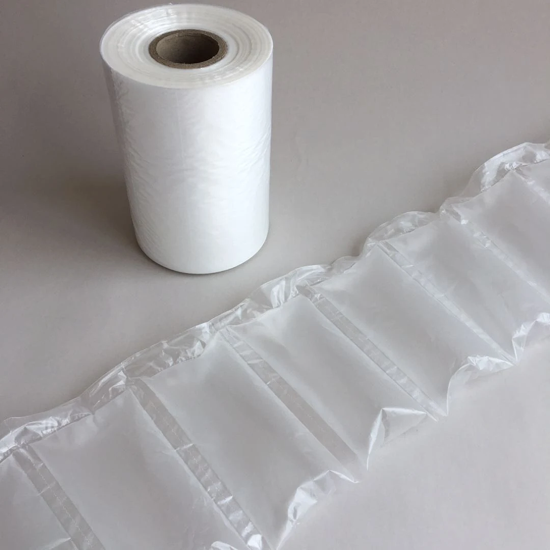 Roll of white air cushion film with cardboard core next to a strip of inflated air pillow packaging on a gray background