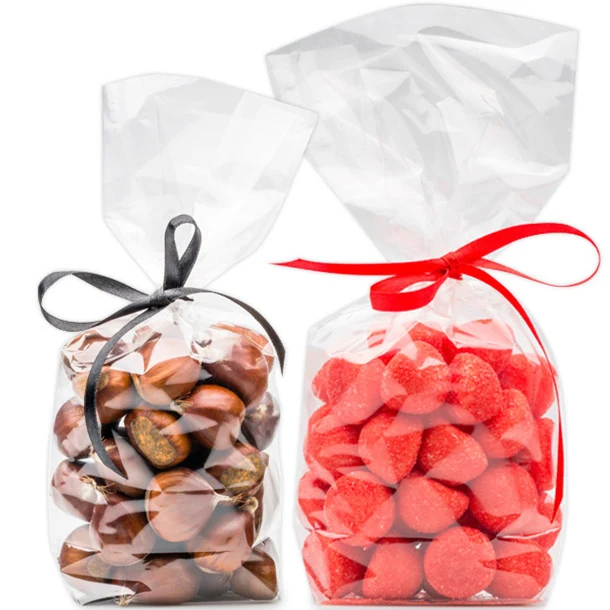 Two clear cellophane bags tied with black and red ribbons, filled with chestnuts and red heart-shaped candies