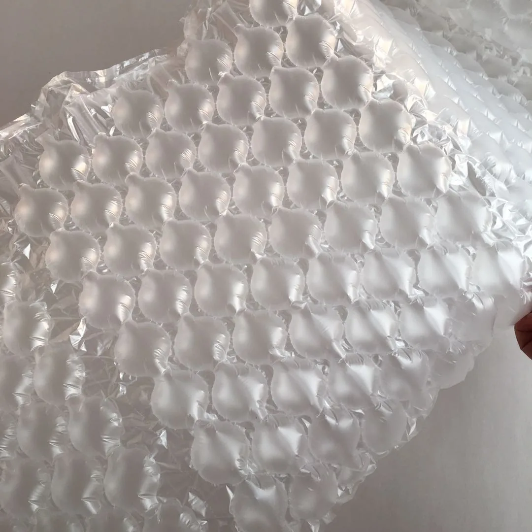 Close-up of translucent air bubble cushioning wrap held by a hand against a plain wall