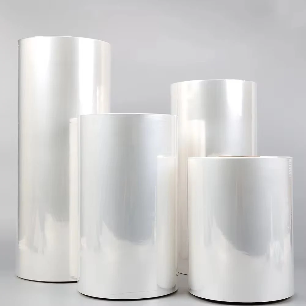 Glossy clear plastic film rolls of various heights standing on a plain light gray background.