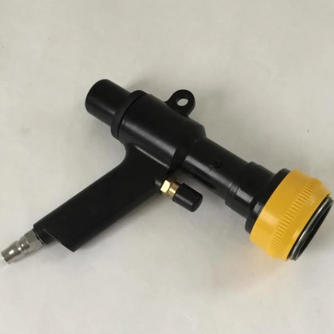 Black handheld tool with yellow ribbed plastic cap, brass fitting and top hanging eyelet on plain background