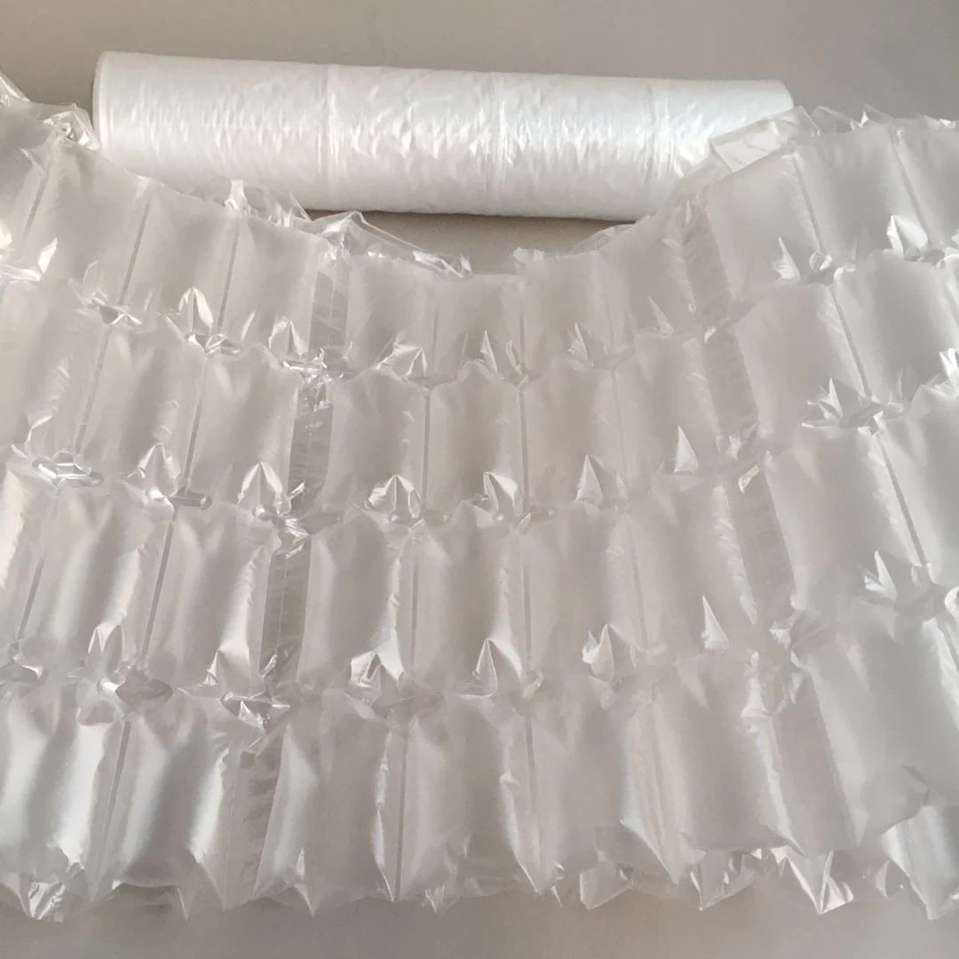 Sheet of inflated clear air pillow packaging in front of a roll of air cushion film on a plain beige surface
