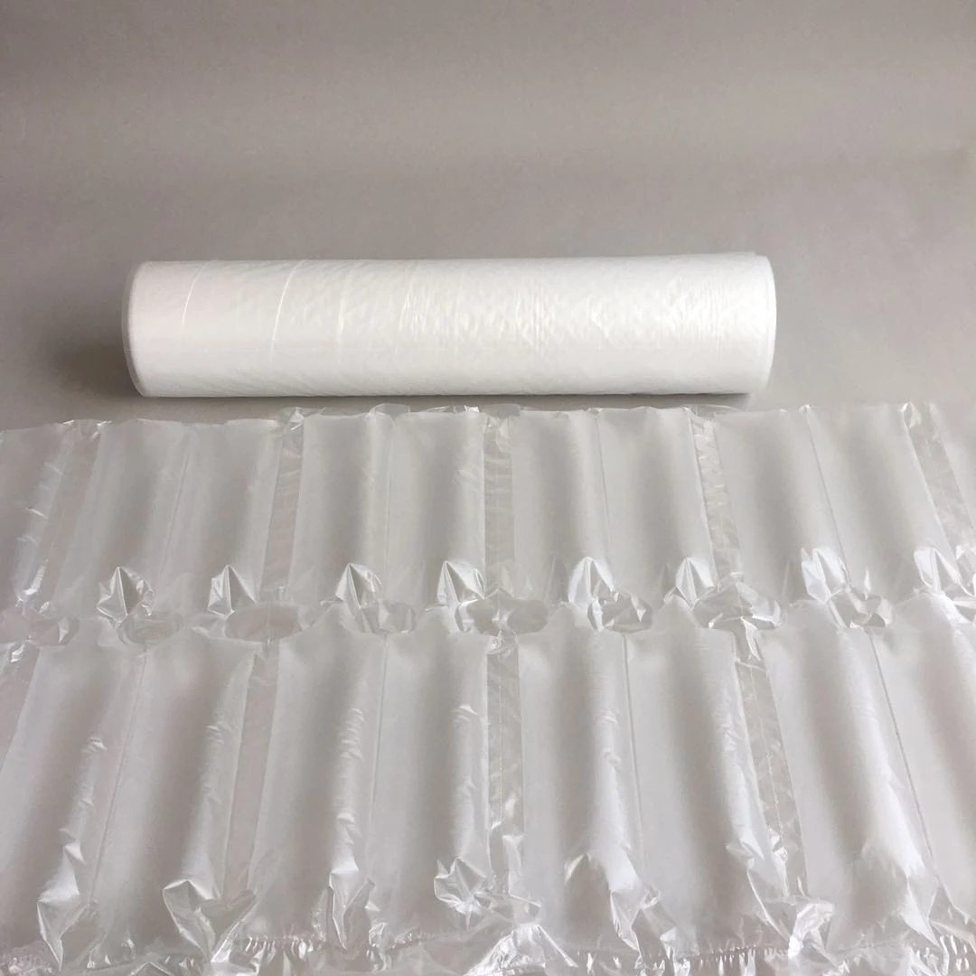 Roll of white plastic film behind a sheet of inflated air cushion packaging columns on a gray surface