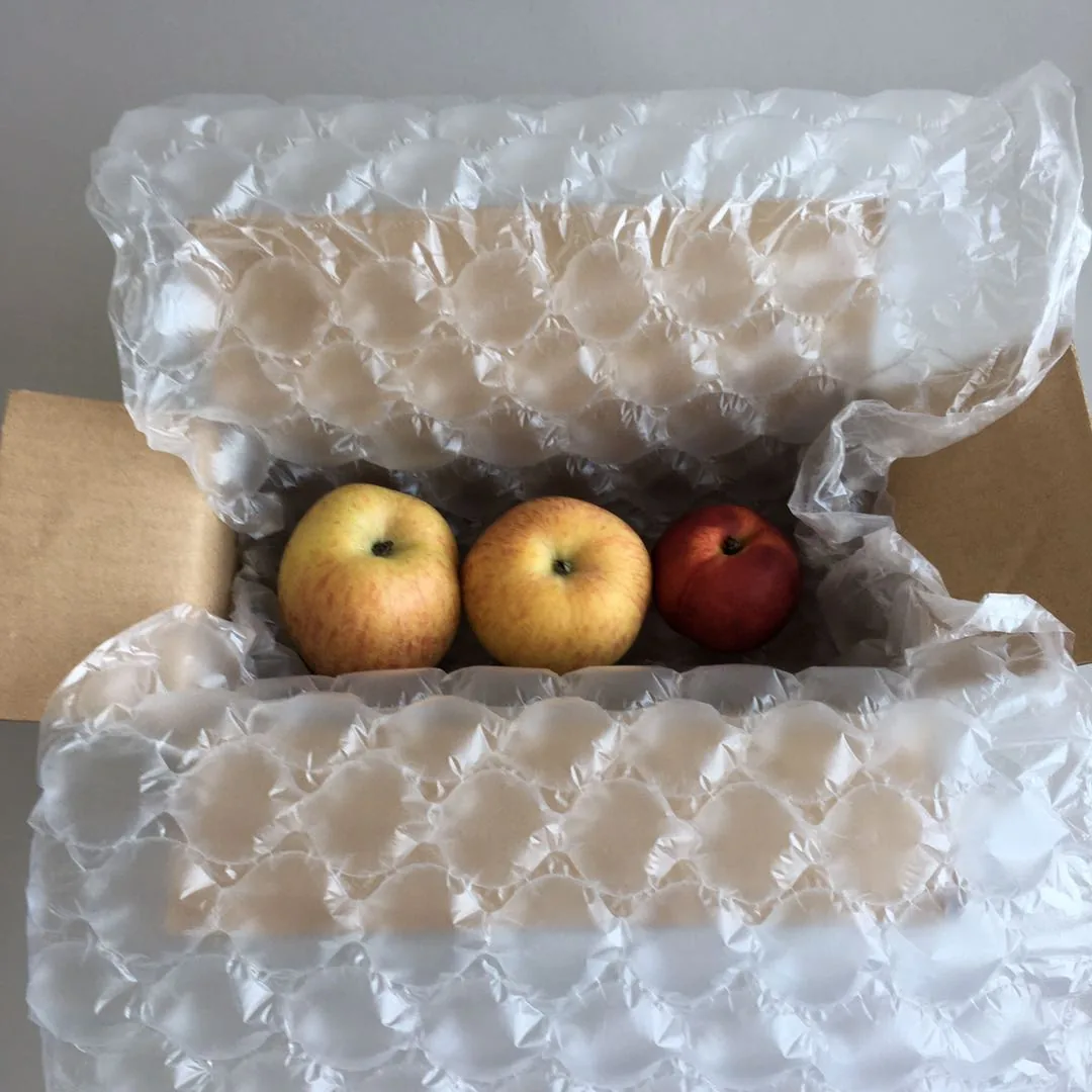 Air cushion packaging film lining a cardboard box filled with apples