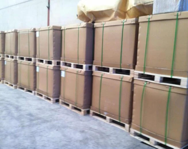Stacks of wooden shipping crates with green strapping bands on pallets in a warehouse