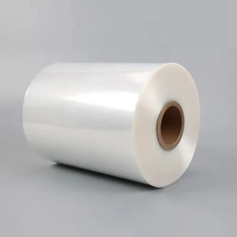 Roll of transparent plastic film with cardboard core on a plain gray background
