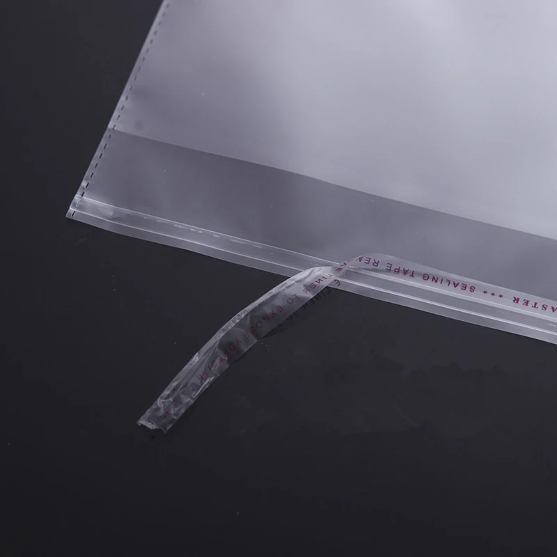 Close-up of a clear plastic mailing bag with a peel-and-seal adhesive strip against a dark background.