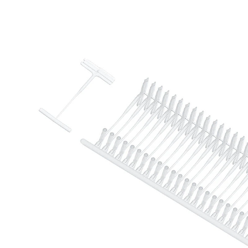 Strip of white plastic T-shaped tag fasteners on a runner, with one loose fastener at left, white background
