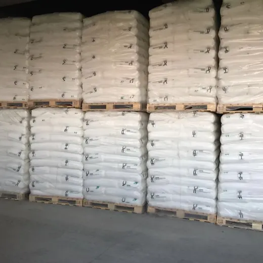 Stacks of shrink-wrapped white sacks on wooden pallets inside a warehouse.