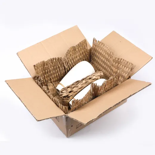 Open cardboard box containing white ceramic bottles wrapped in kraft honeycomb paper cushioning on a white background