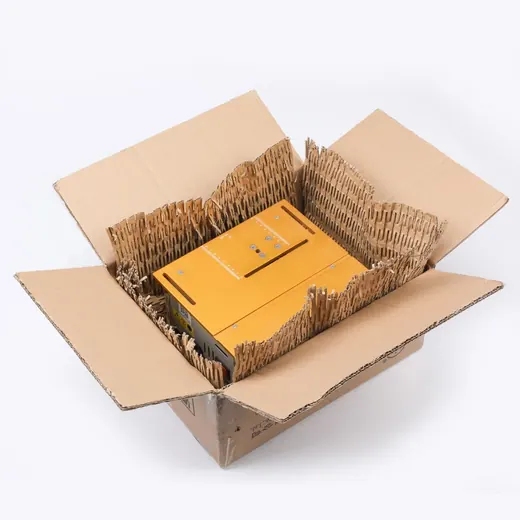 An open cardboard shipping box containing a yellow device protected by corrugated paper inserts.