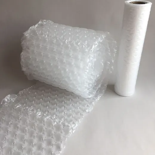 A roll of bubble wrap and a roll of stretch film standing upright on a white surface.