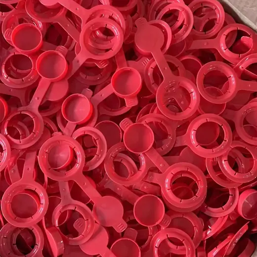 Bulk pile of red plastic flip-top tethered caps with round bases and hinged lids