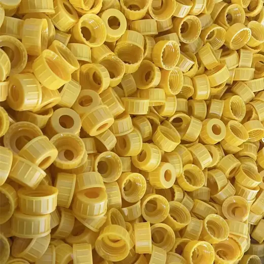 Bulk pile of yellow ribbed plastic screw caps filling the entire frame