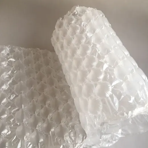 Roll of translucent air bubble cushioning wrap standing upright beside a flat sheet on a plain background