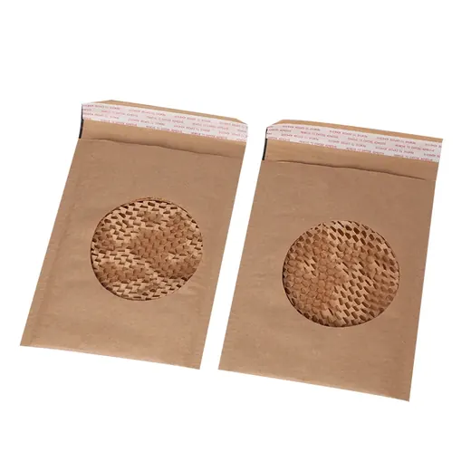 Two brown kraft paper bags with circular windows containing honeycomb packing paper on a white background