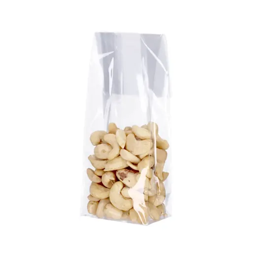Transparent cellophane bag filled with cashew nuts standing upright on a white background