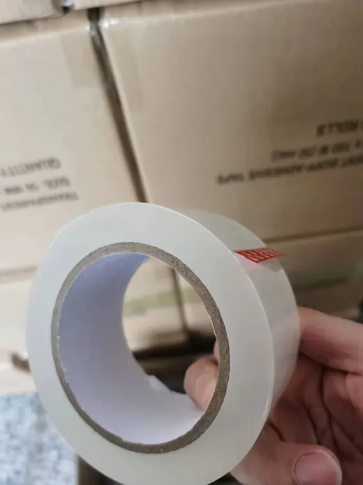 Roll of clear adhesive tape held in hand against cardboard boxes