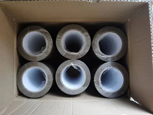 Six rolls of clear tape packed inside an open corrugated cardboard box