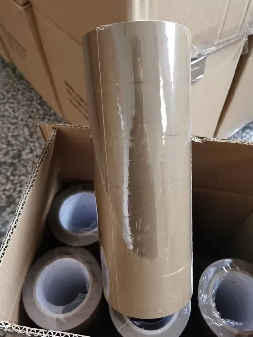 Rolls of brown BOPP packing tape stacked inside an open cardboard box in a warehouse